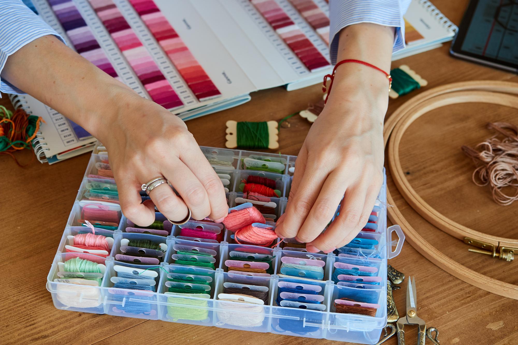 artisan arranging embroidered samples on a table